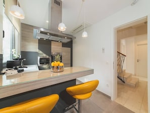 Una cocina moderna con una isla central, electrodomésticos de acero inoxidable y un frutero.