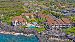 A coastal resort with multiple buildings, a swimming pool, and a rocky shoreline. - Sea Village #4114 (Kailua-Kona)