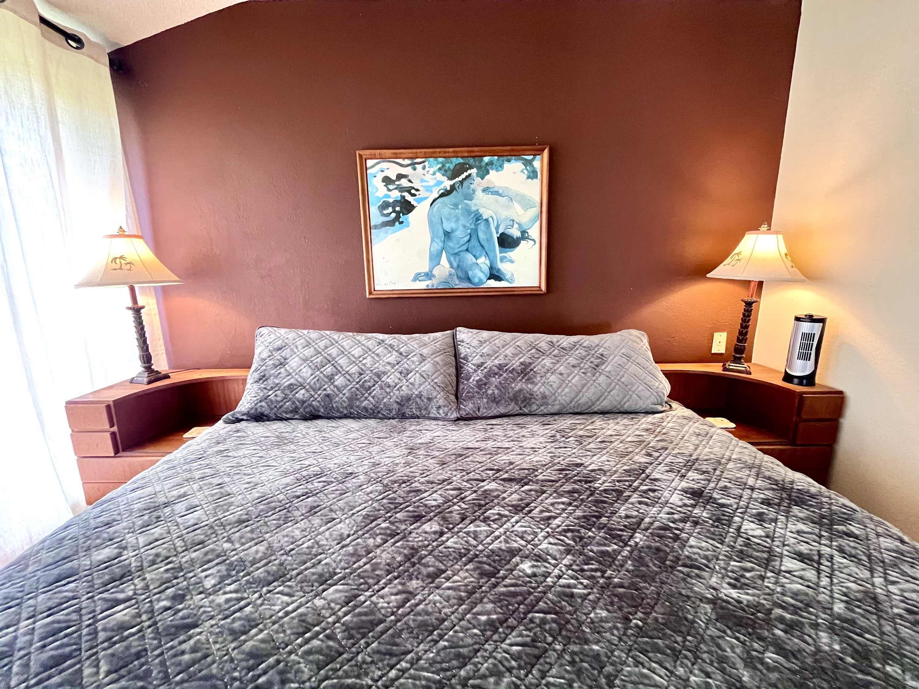 A hotel room with a bed, two bedside lamps, a framed artwork on the wall, and a nightstand with a lamp.
