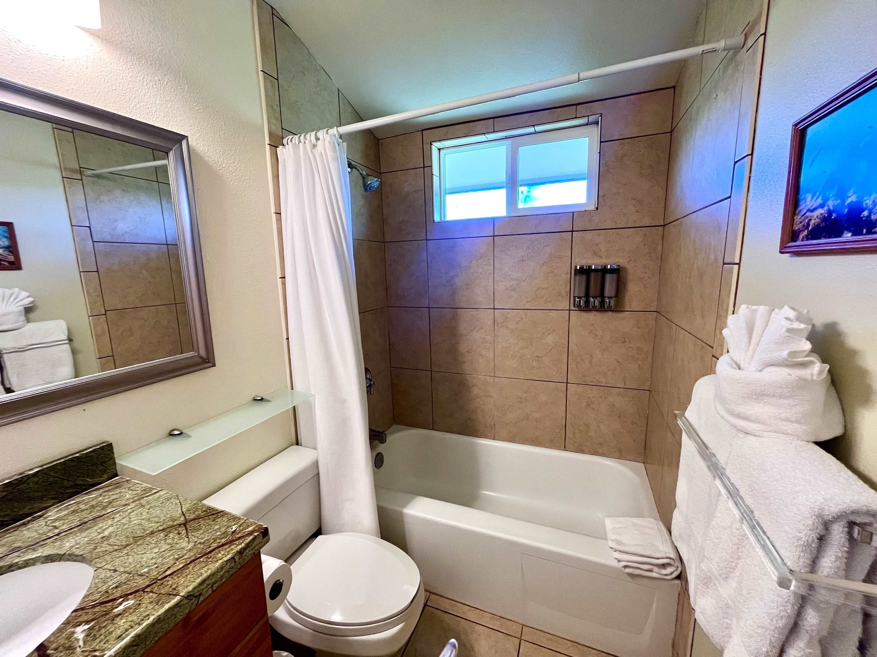 A bathroom with a bathtub, toilet, and shower curtain.