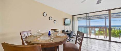 A dining area with a round table, chairs, and a television on the wall.
