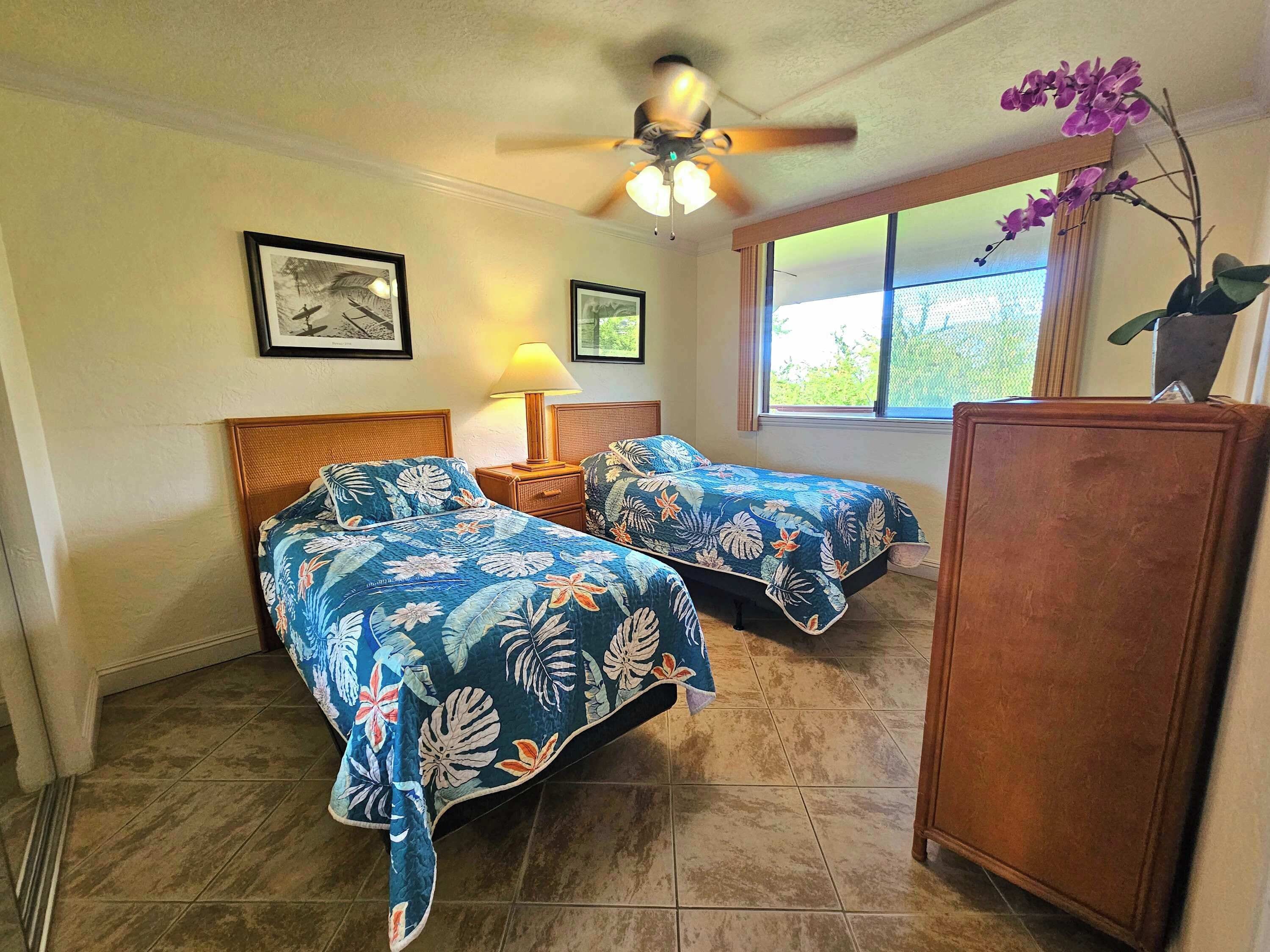 Una habitación con dos camas, ventilador de techo, ventana con vistas y un armario.