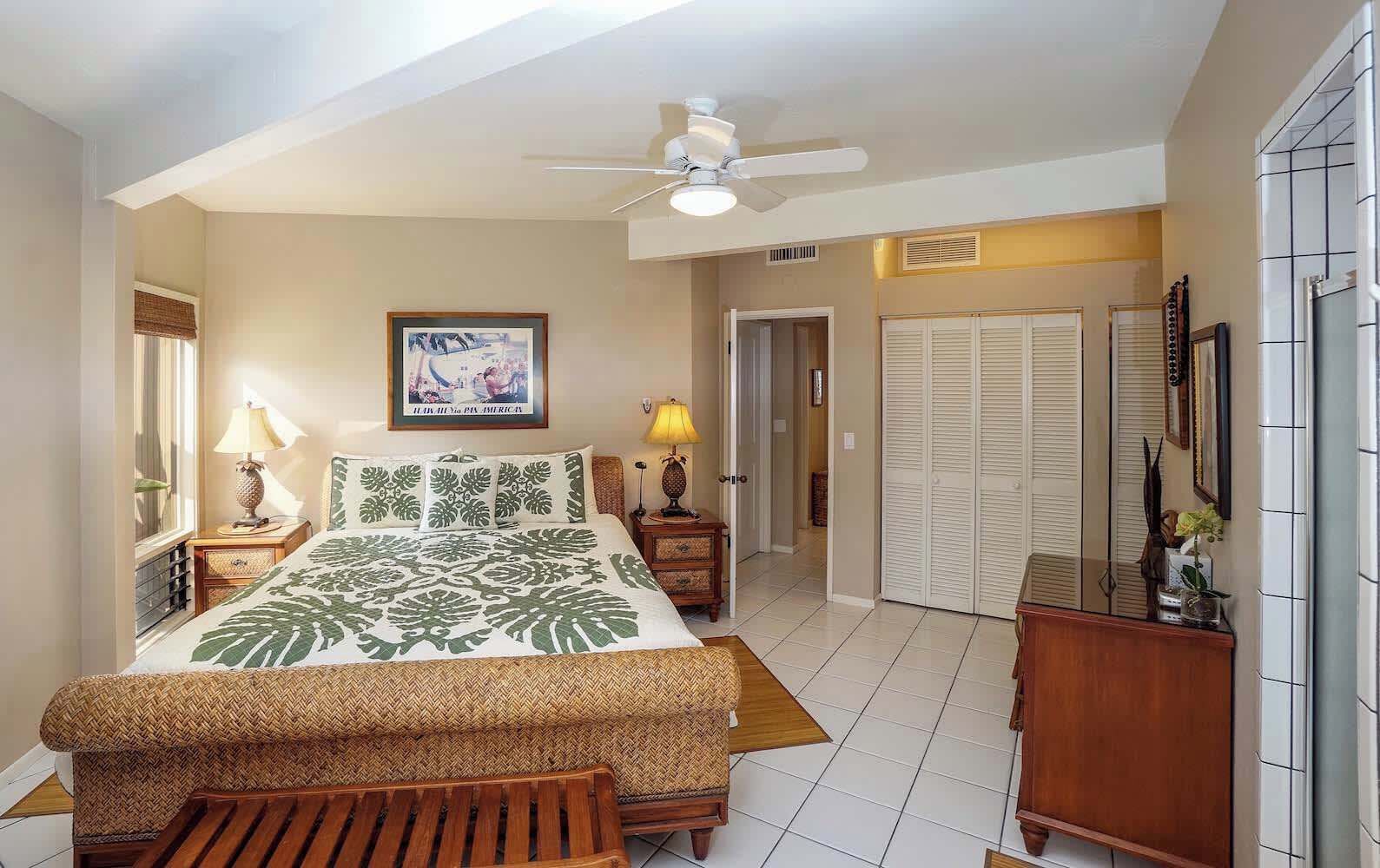 Ein Schlafzimmer mit Bett, Nachttischen, Deckenventilator, gerahmtem Bild und Kleiderschrank.