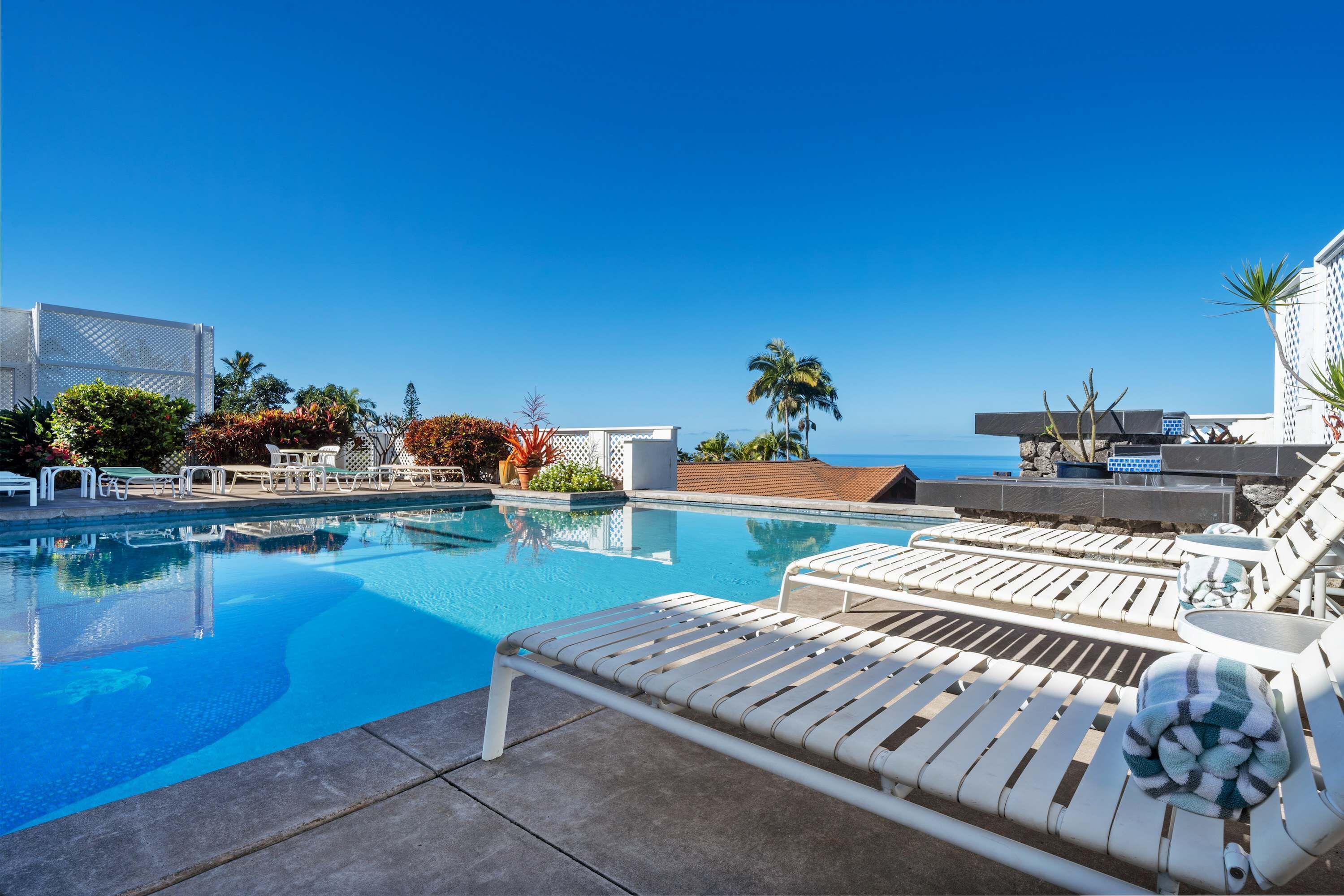 A poolside area with lounge chairs and a view of the ocean.