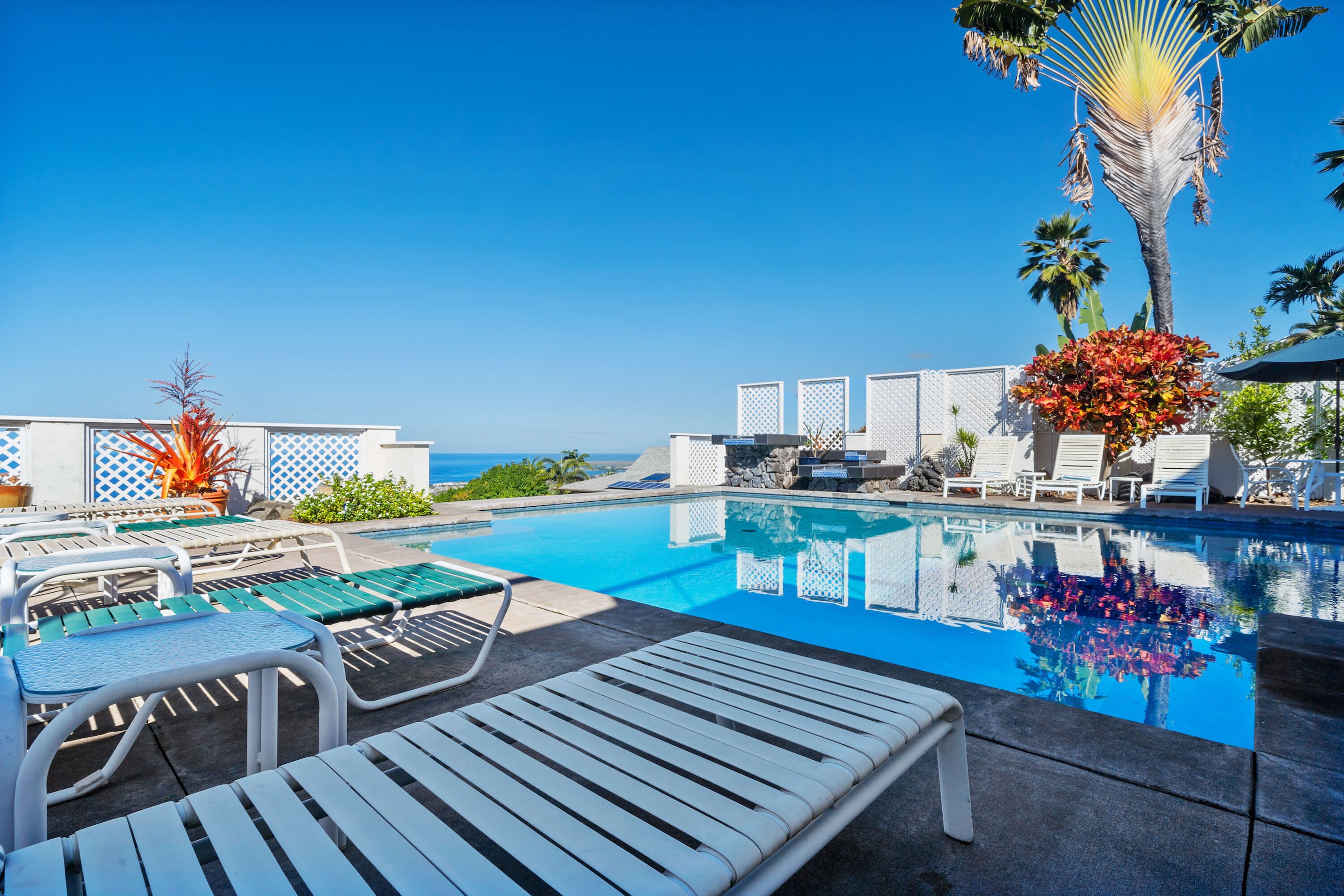 A poolside area with lounge chairs and a view of the ocean.
