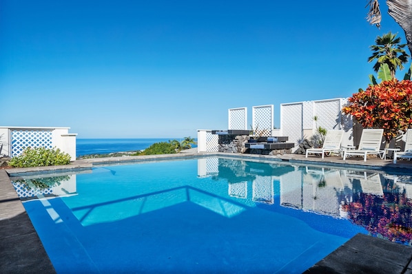 Una piscina al aire libre, sillones reclinables de piscina