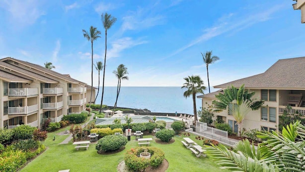 A resort with multiple-story buildings, a central pool area, and a view of the ocean.