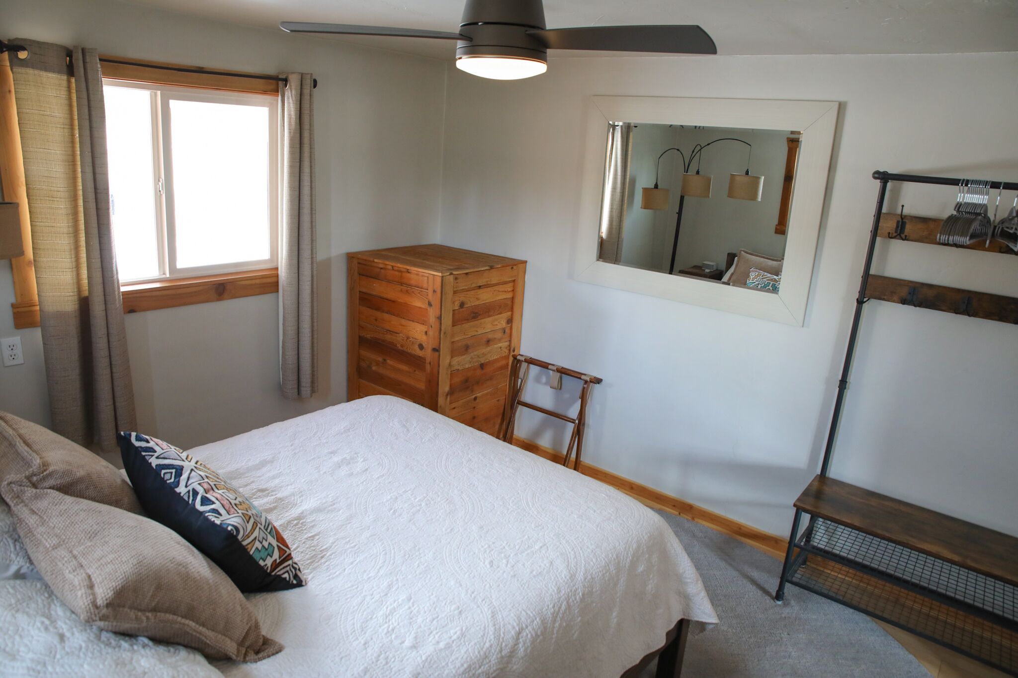 Une chambre à coucher comprenant un lit, une armoire en bois, un miroir et une étagère.