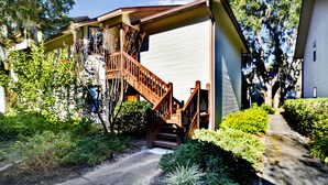 A two-story house with a wooden staircase leading to the front door.