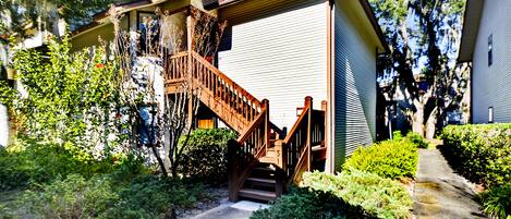 A two-story house with a wooden staircase leading to the front door.