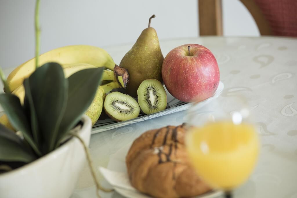 A table with a plate of fruits, a potted plant, and a muffin.