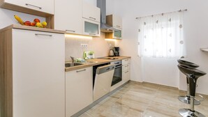 Una cocina moderna con horno empotrado, cafetera y una cesta de fruta en la encimera.