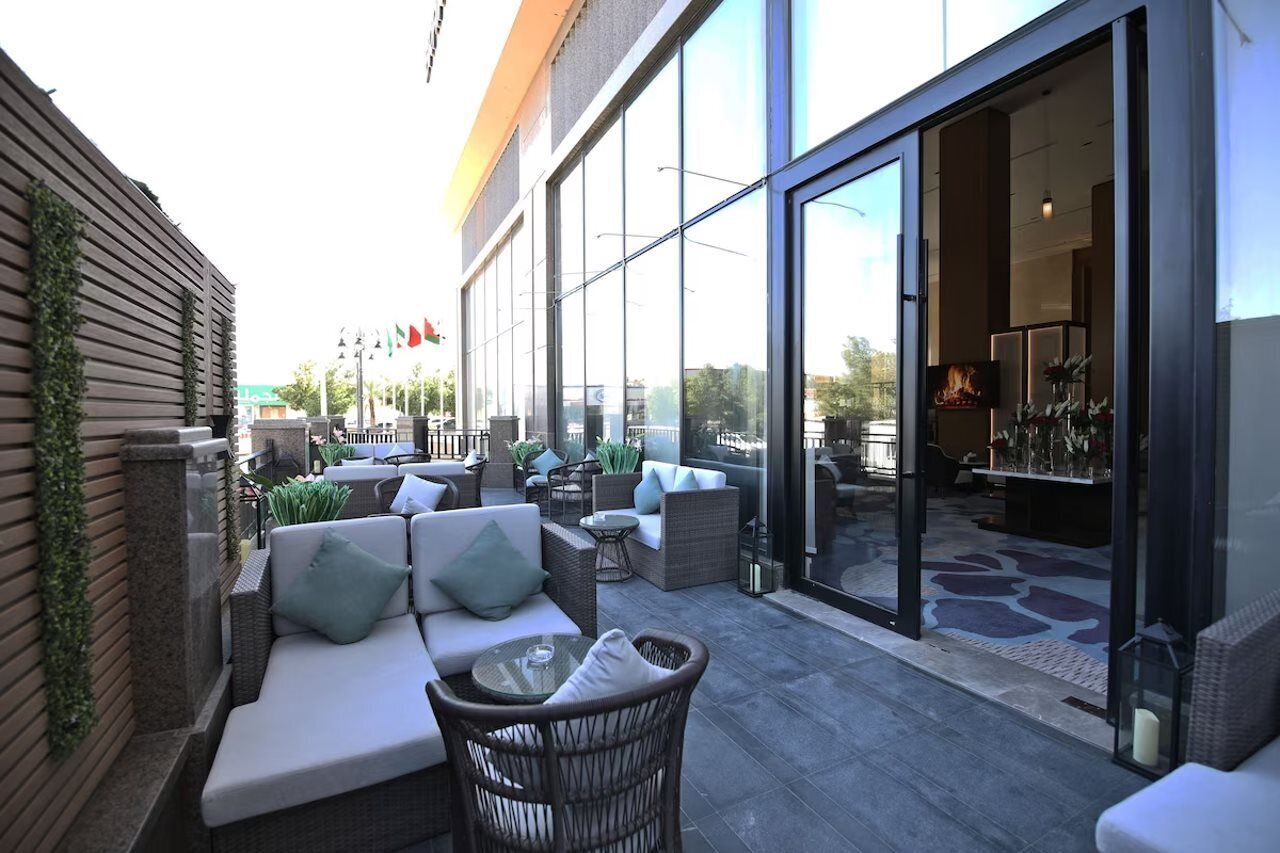 An outdoor seating area with sofas and chairs, a glass door entrance, and a view of the street.