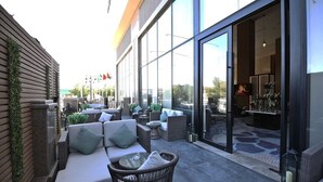 An outdoor seating area with sofas and chairs, a glass door entrance, and a view of the street. - Braira Al Yarmouk Hotel (Riyadh)