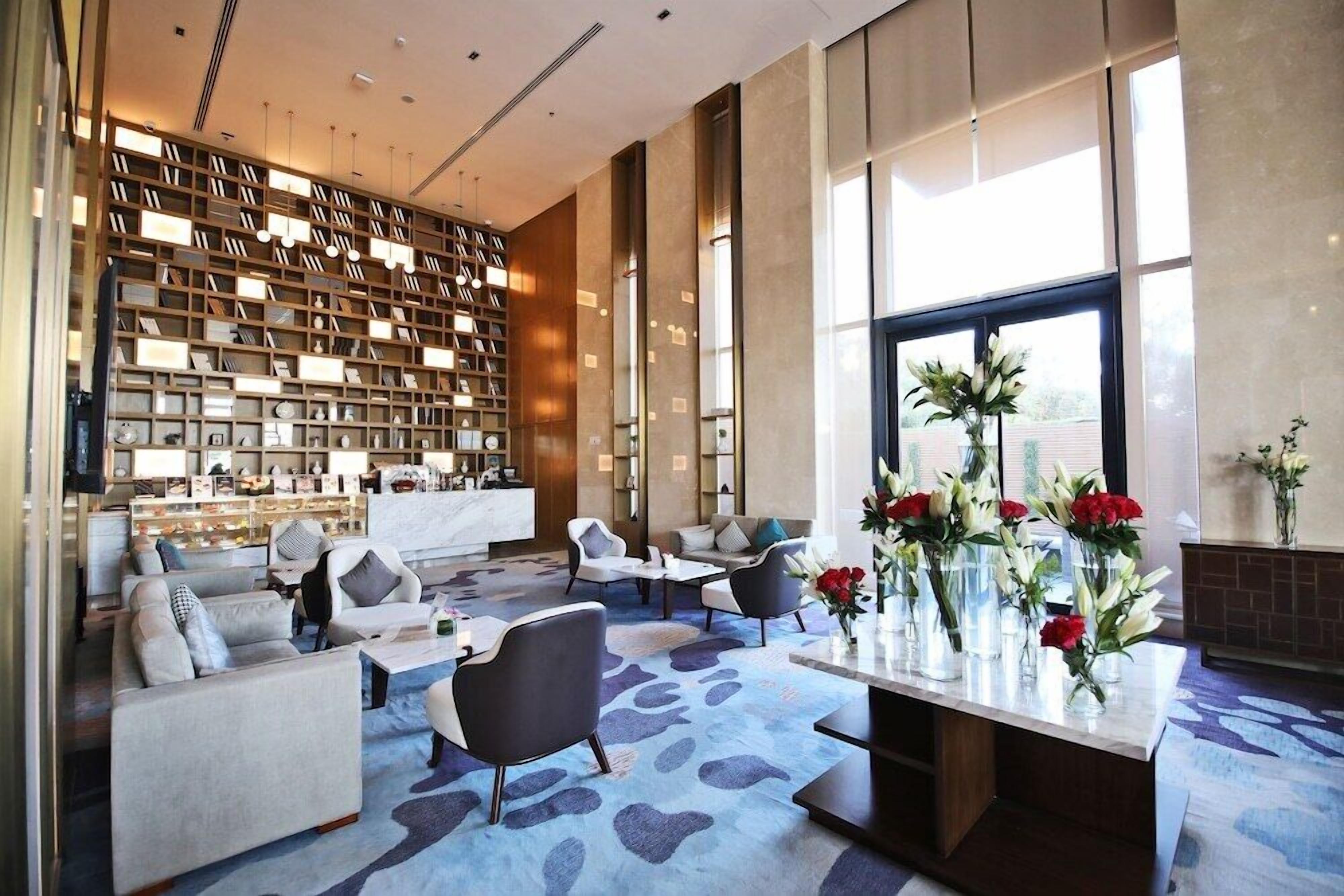 A modern lobby with a large bookshelf, seating area, and a view of the outdoors.
