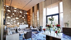 A modern lobby with a large bookshelf, seating area, and a view of the outdoors. - Braira Al Yarmouk Hotel (Riyadh)