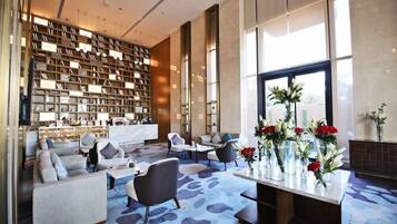 A modern lobby with a large bookshelf, seating area, and a view of the outdoors.