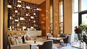 A modern lobby with a large bookshelf, seating area, and a reception desk. - Braira Al Yarmouk Hotel (Riyadh)