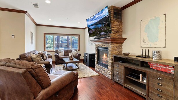 A living room with a stone fireplace, leather sofas, a flat-screen TV, and a map on the wall. - Tahoe Woods Villa - Walk to Beach and Gondola/ Heavenly Ski (South Lake Tahoe)