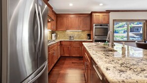 A modern kitchen with wooden cabinets, stainless steel appliances, and a granite countertop. - Tahoe Woods Villa - Walk to Beach and Gondola/ Heavenly Ski (South Lake Tahoe)