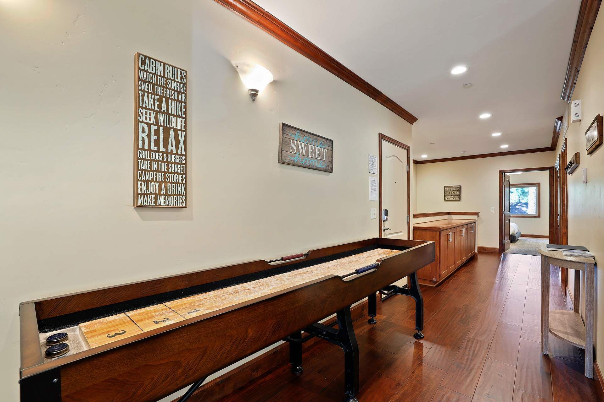 A wooden bench with a game table, a wall with cabin rules, and a sign that says "SWEET home."