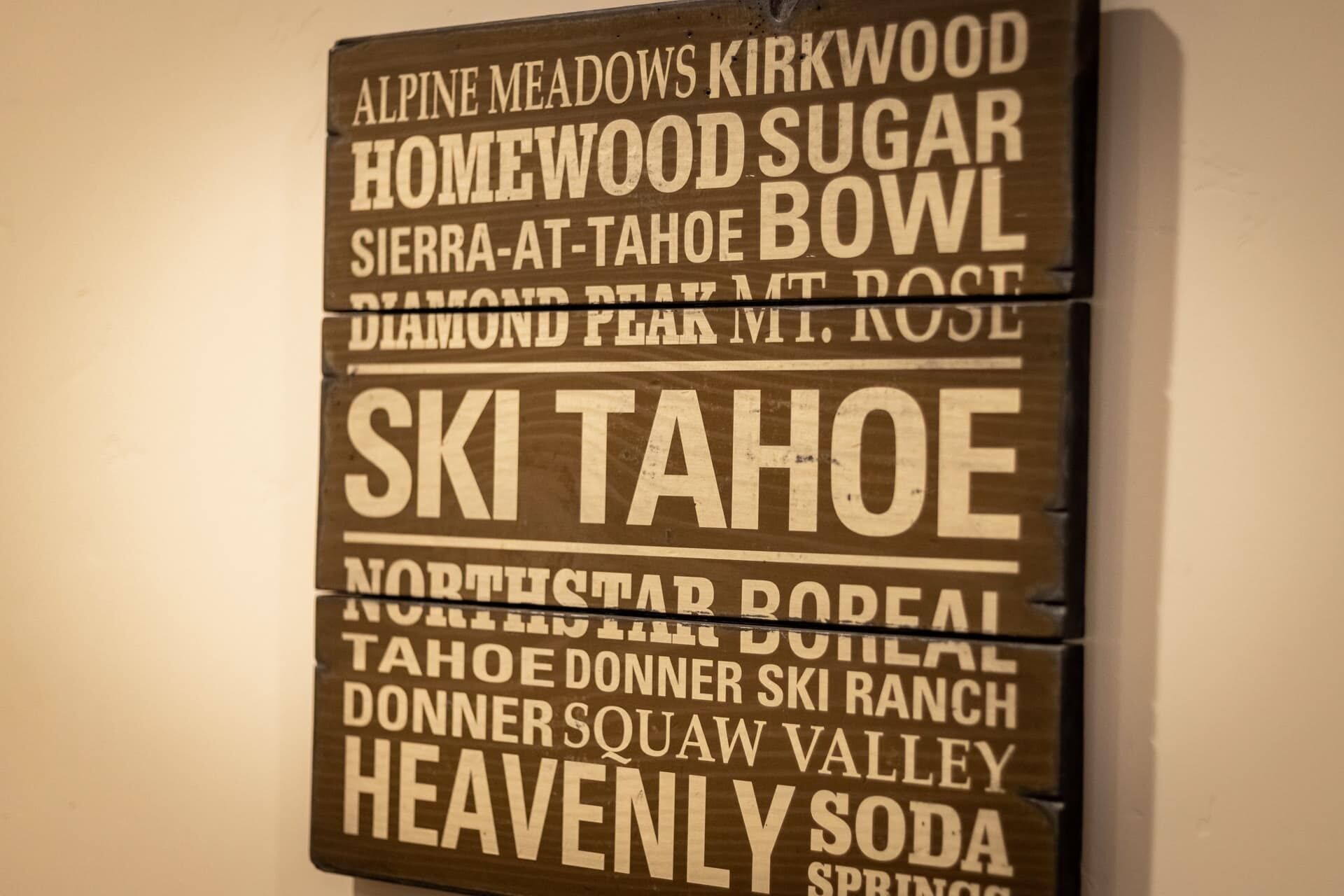 Un letrero de madera con varios nombres de estaciones de esquí.
