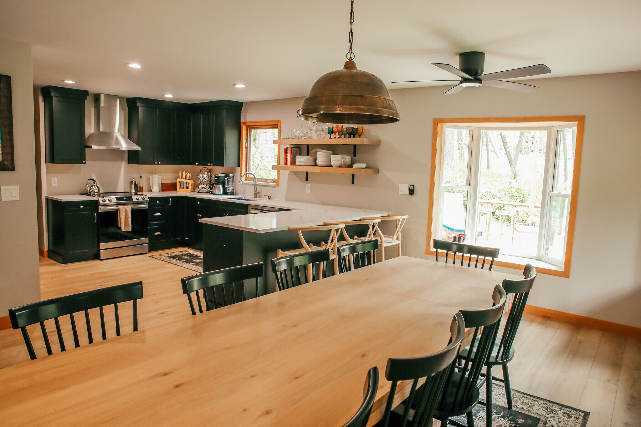 Een moderne keuken met donkere kasten, een centraal eiland en een eethoek met een houten tafel en stoelen.