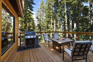 A wooden deck with a grill, chairs, and a fire pit.