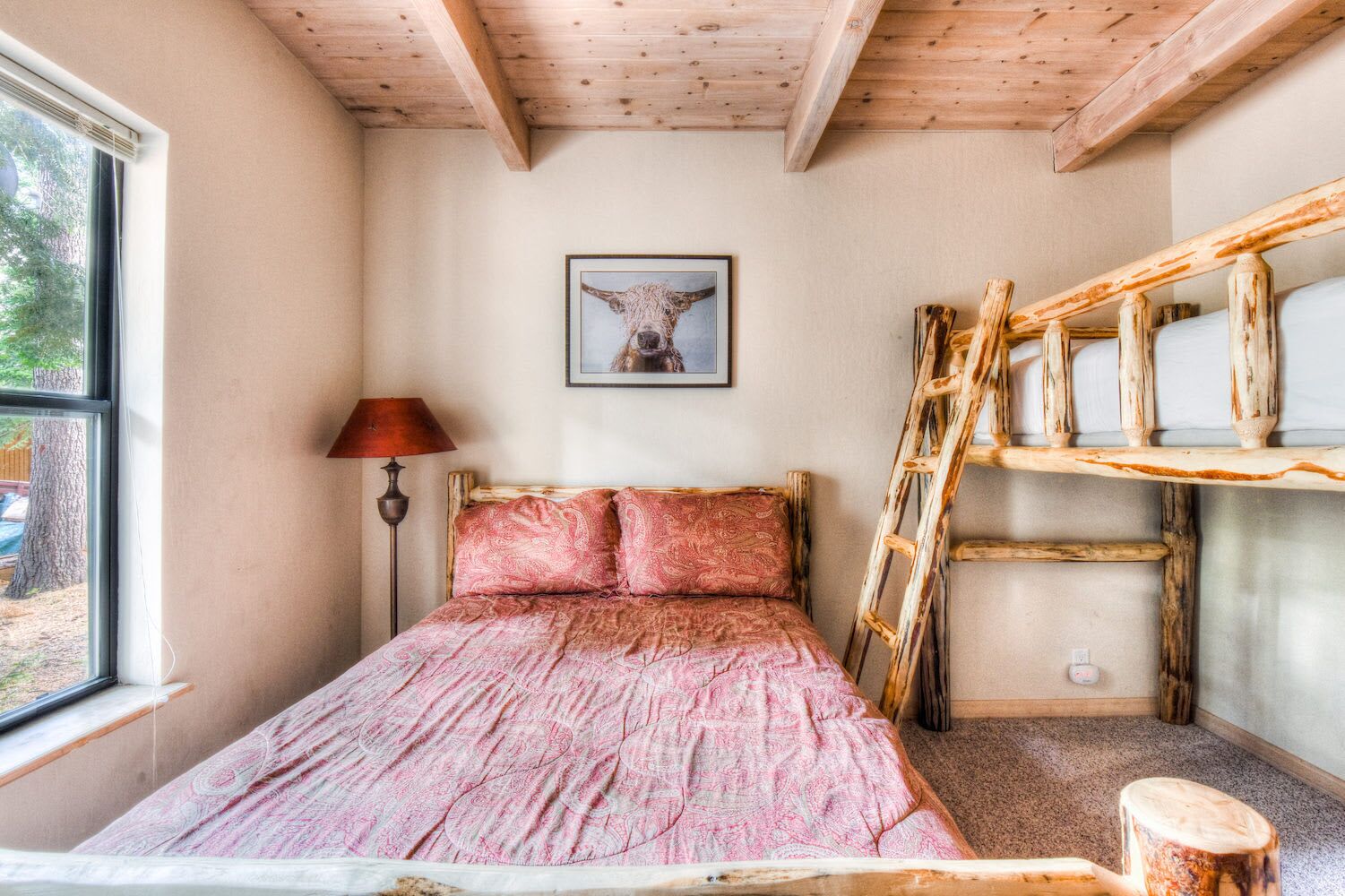 A bedroom with a bed, a wooden ladder, a lamp, and a framed picture on the wall.