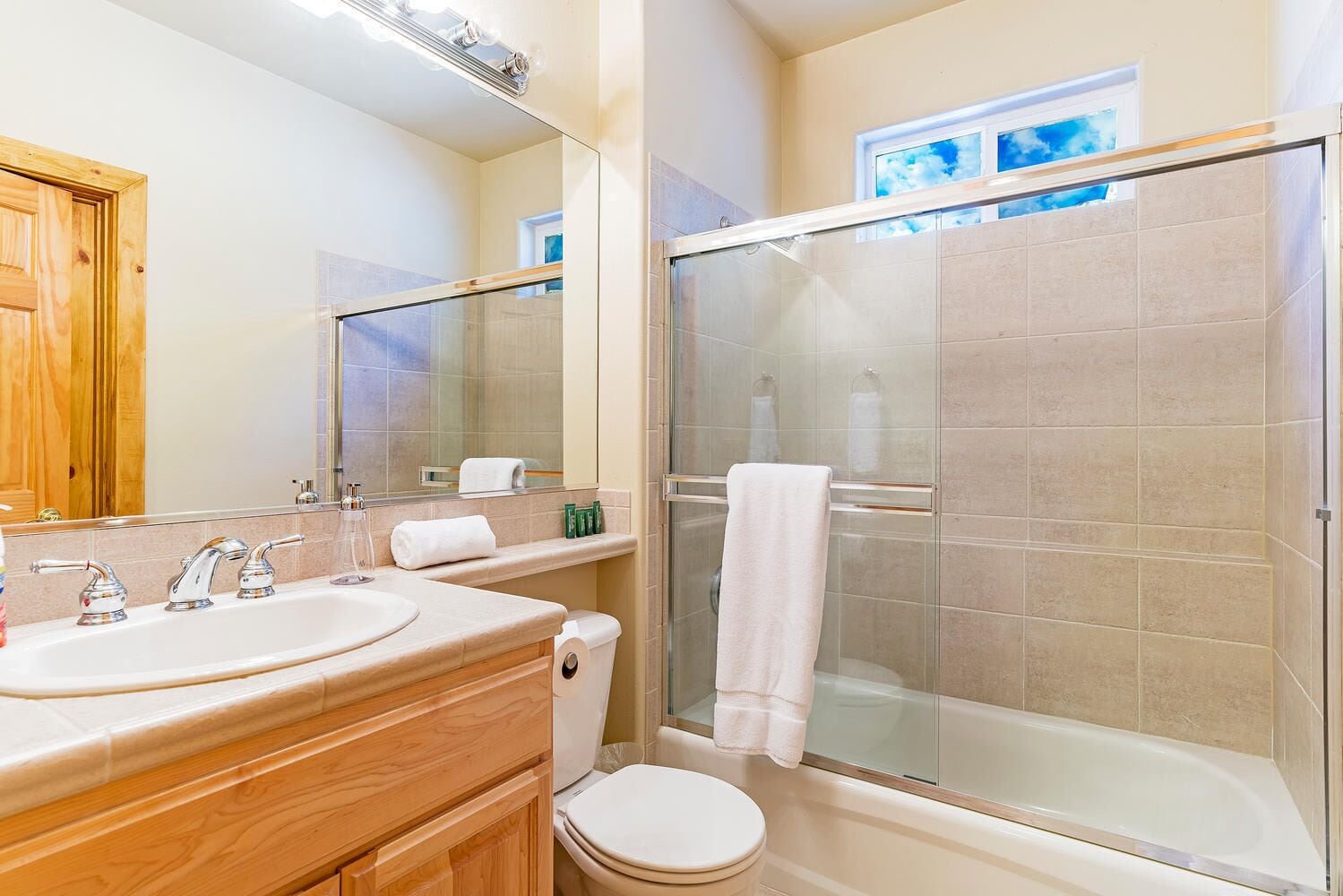 Une salle de bain avec deux lavabos, des toilettes, une douche à parois de verre et un grand miroir.