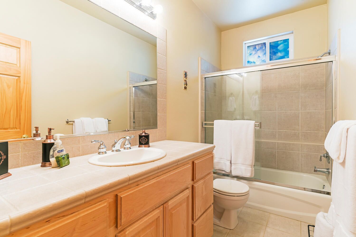 Une salle de bain avec un meuble-lavabo en bois, un évier, un miroir, une cabine de douche et des toilettes.