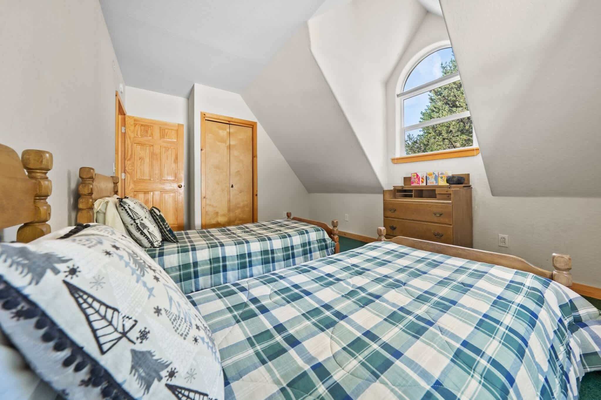 Un dormitorio con dos camas, cabeceros de madera, un aparador de madera, una ventana y una puerta.