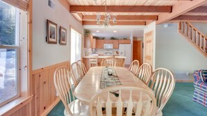 A dining area with a wooden table and chairs, a chandelier, and a view of the kitchen and staircase. - Mckinney Estate w/ Roof Deck Beach & Hike! (Tahoma)