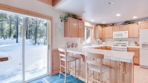 A modern kitchen with wooden cabinets, a central island with bar stools, a microwave, a stove, and a refrigerator. - Mckinney Estate w/ Roof Deck Beach & Hike! (Tahoma)