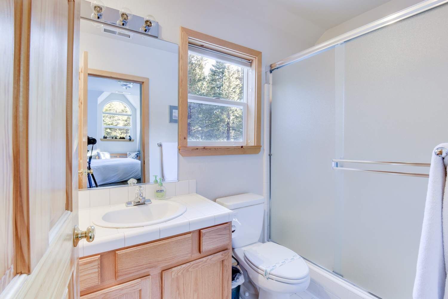 Un baño con tocador de madera, lavamanos blanco, inodoro y ducha.
