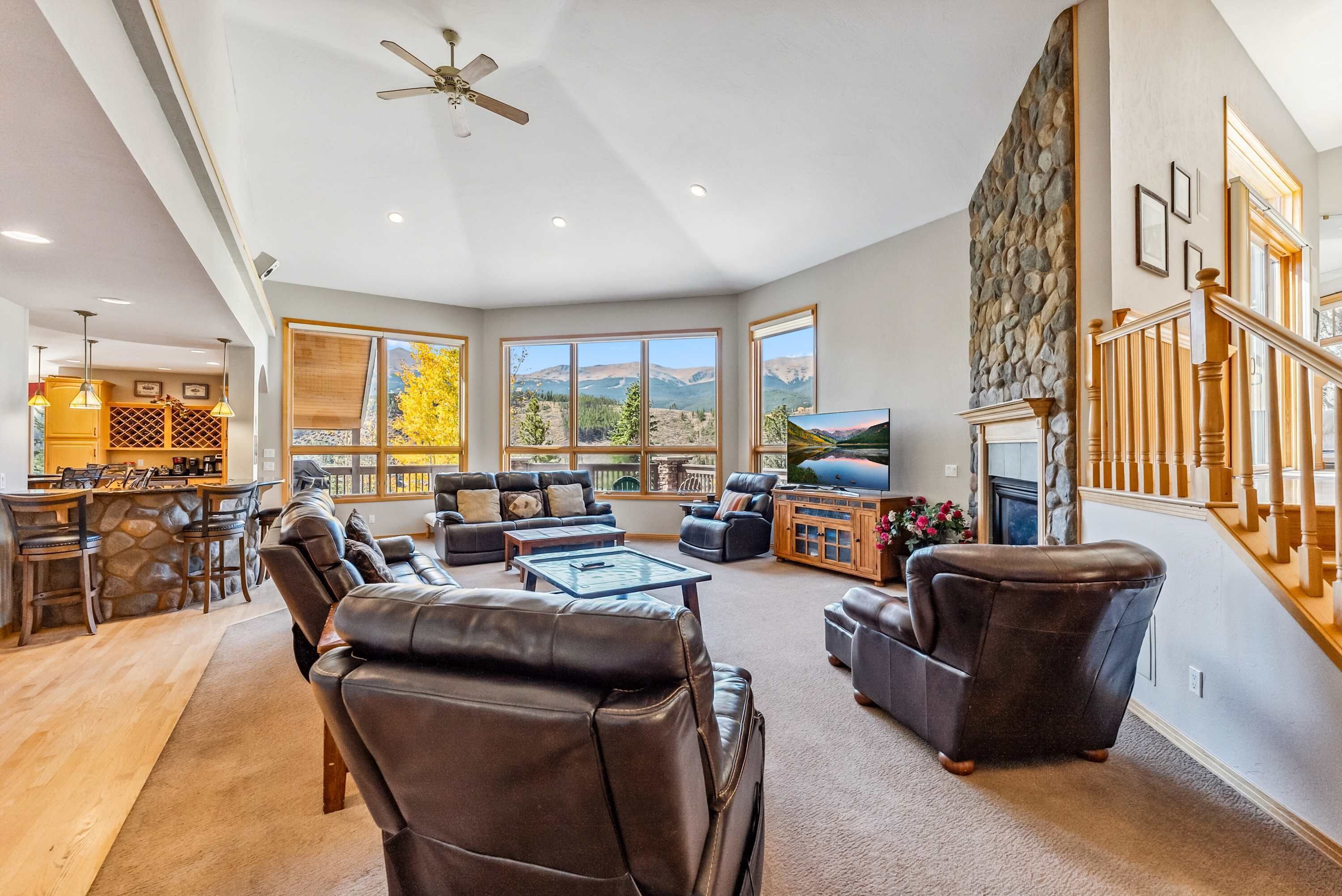 A spacious living room with leather sofas, a TV, and a stone accent wall.