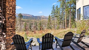 A stone wall and wooden deck with Adirondack chairs overlooking a mountainous landscape. - Massive Breckenridge Estate: Game Room & Hot Tub! (Breckenridge)