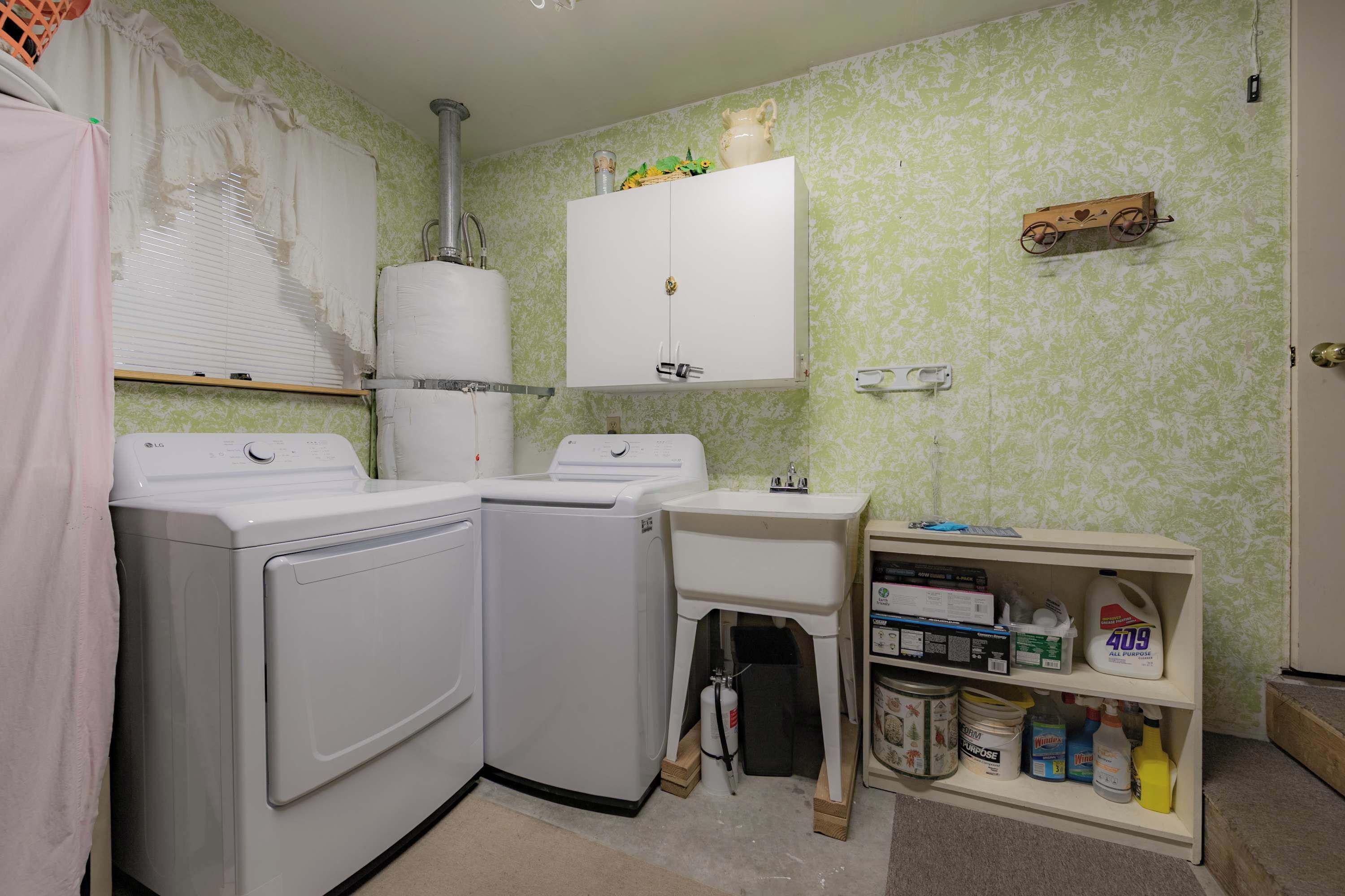 Un área de lavandería con dos lavadoras, un lavabo y un estante con productos de limpieza.