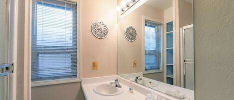 A bathroom with two sinks, a large mirror, and decorative wall sconces.