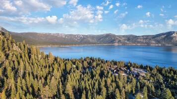 A mountainous landscape with a lake, dense forest, and a small settlement with buildings.