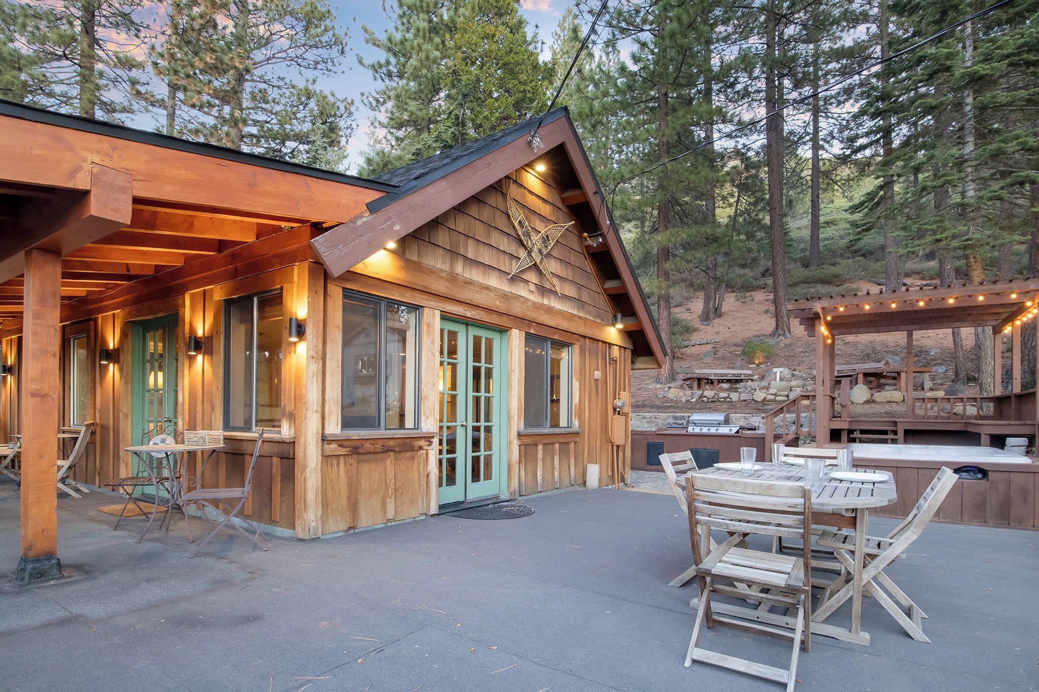 A wooden cabin with a covered patio, outdoor seating, and a barbecue area.