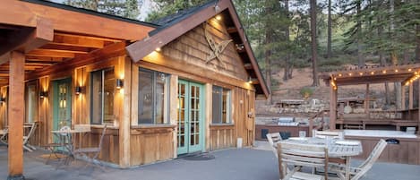 A wooden cabin with a covered patio, outdoor seating, and a barbecue area.