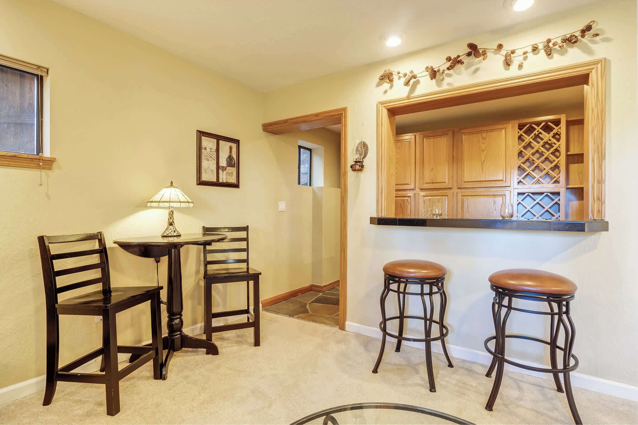 Un comedor con una mesa y sillas, una barra con taburetes y una pared decorativa.