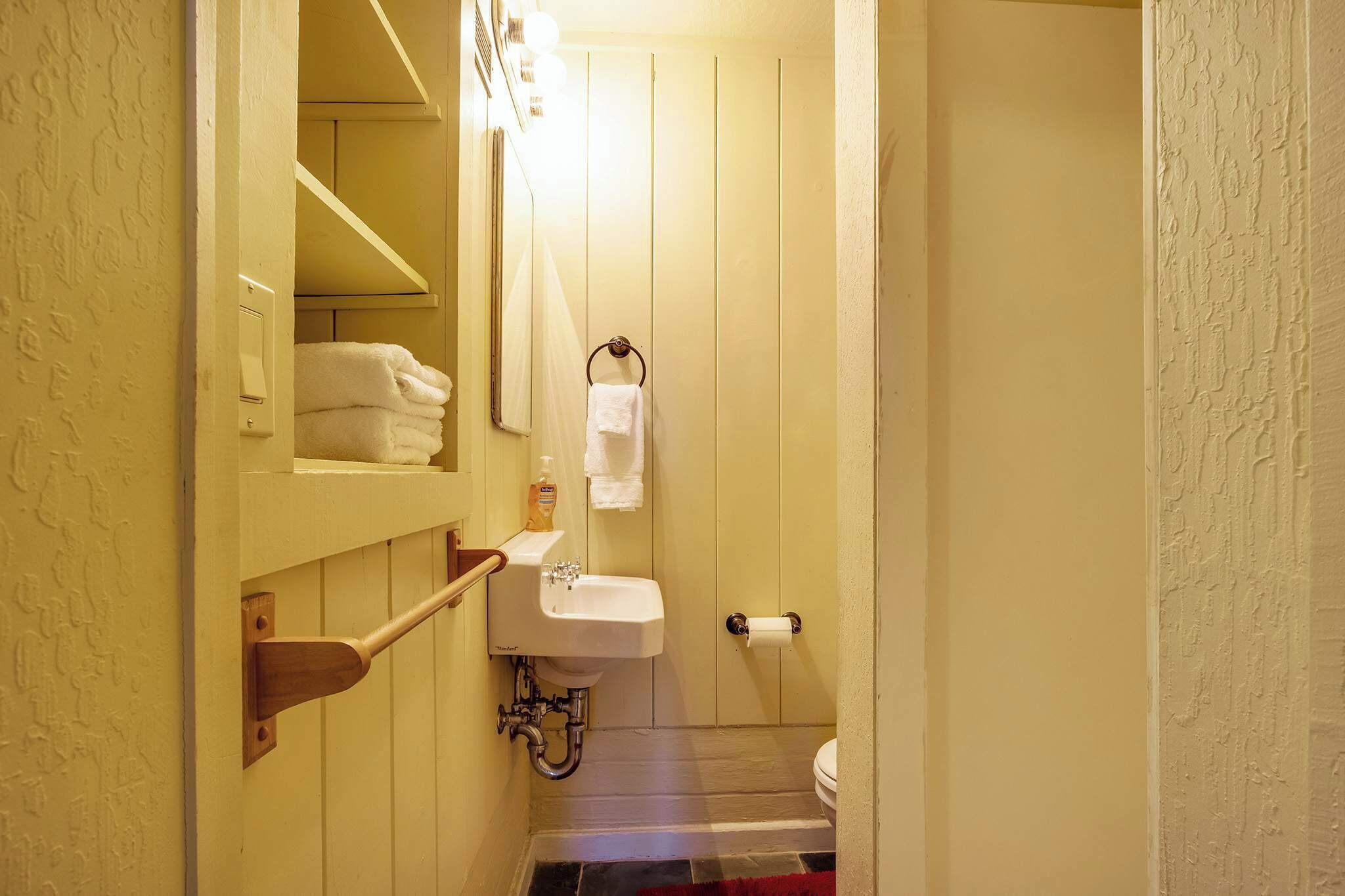 Et lille badeværelse med håndvask, toilet og håndklædestang.