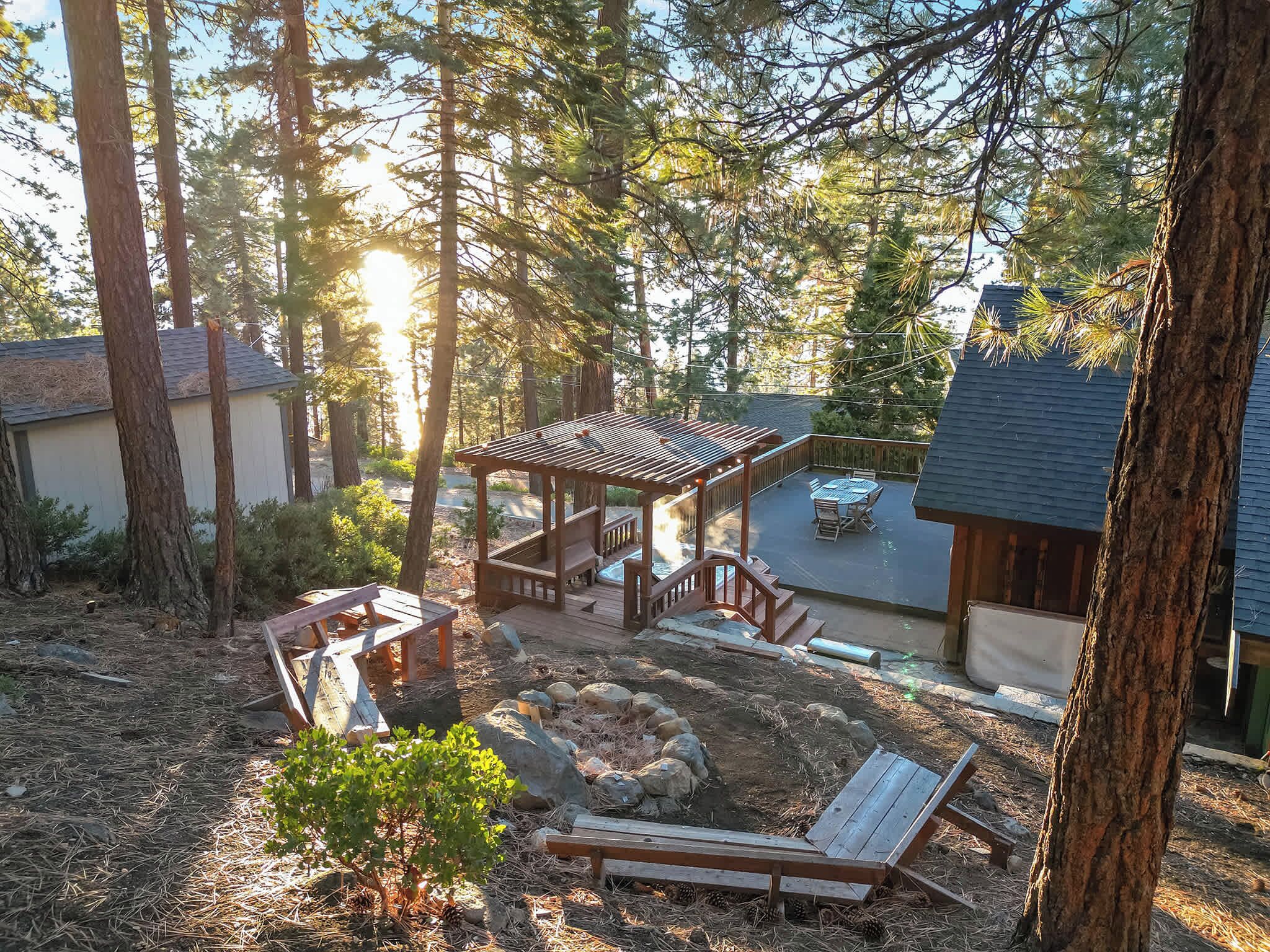 Um deck de madeira com pérgola, lareira e uma cadeira de descanso.