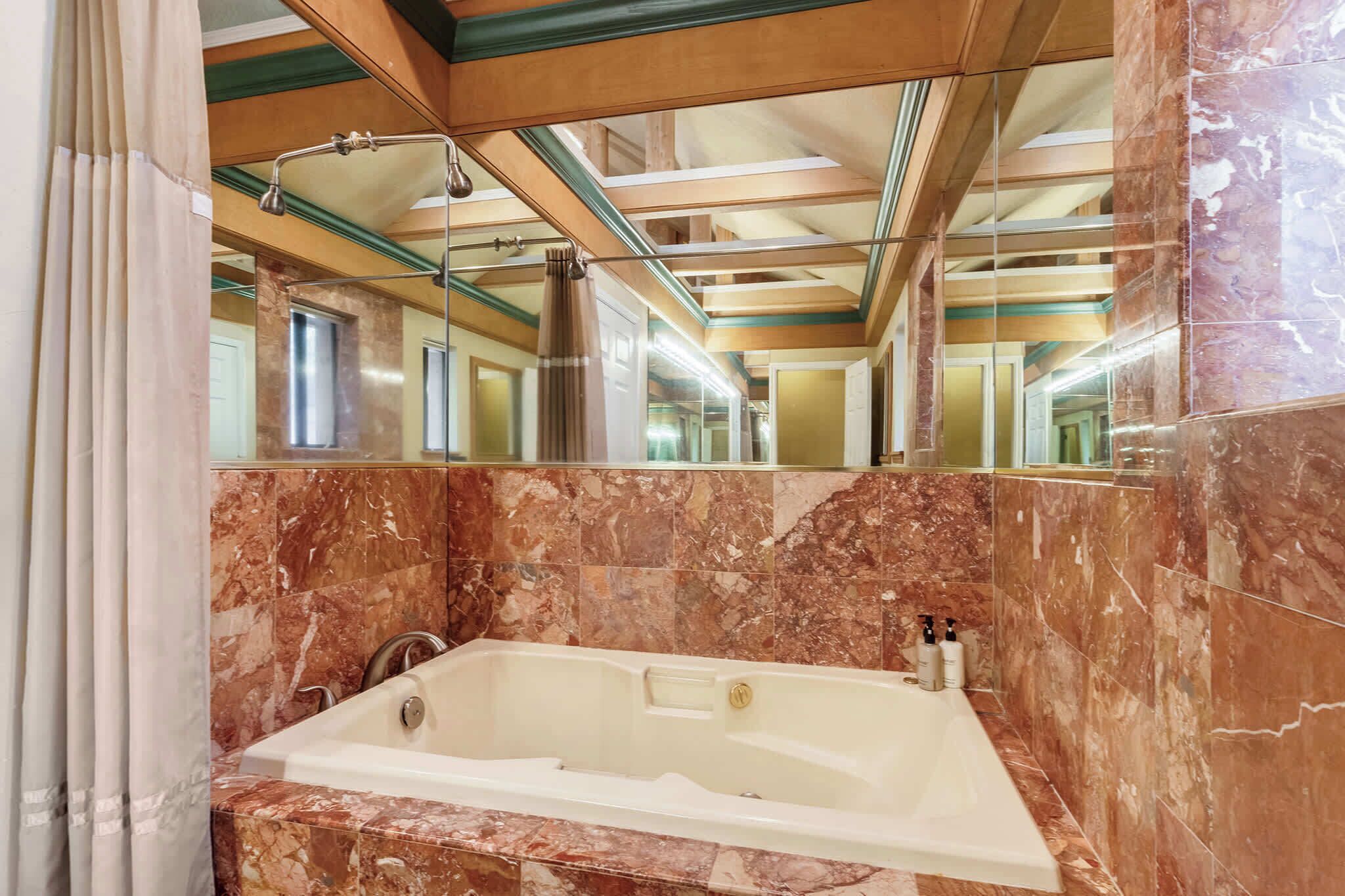 Ein Badezimmer mit Marmorwand, einer Badewanne und einem Spiegel.