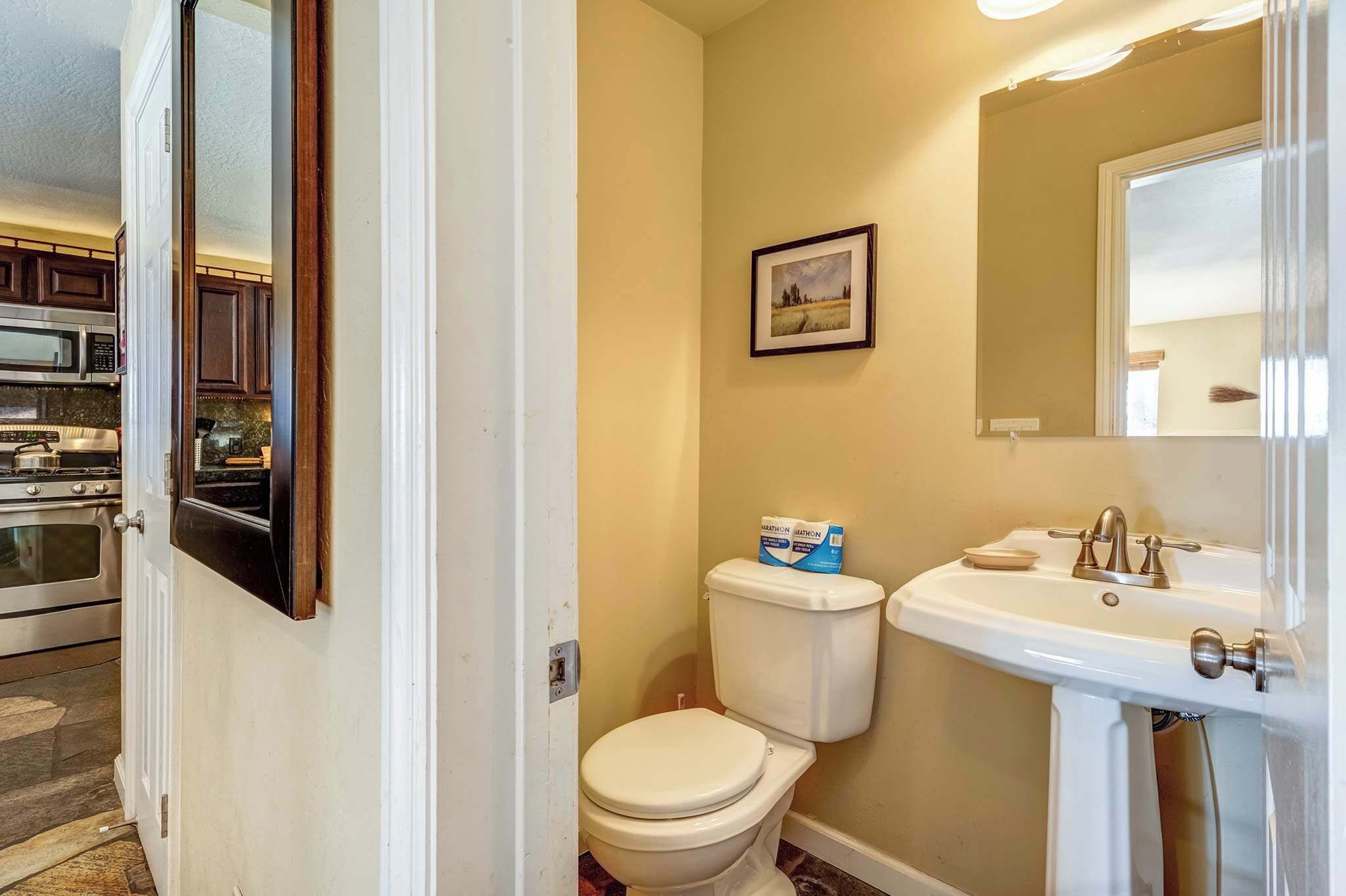 A bathroom with a toilet, sink, and a framed picture on the wall.