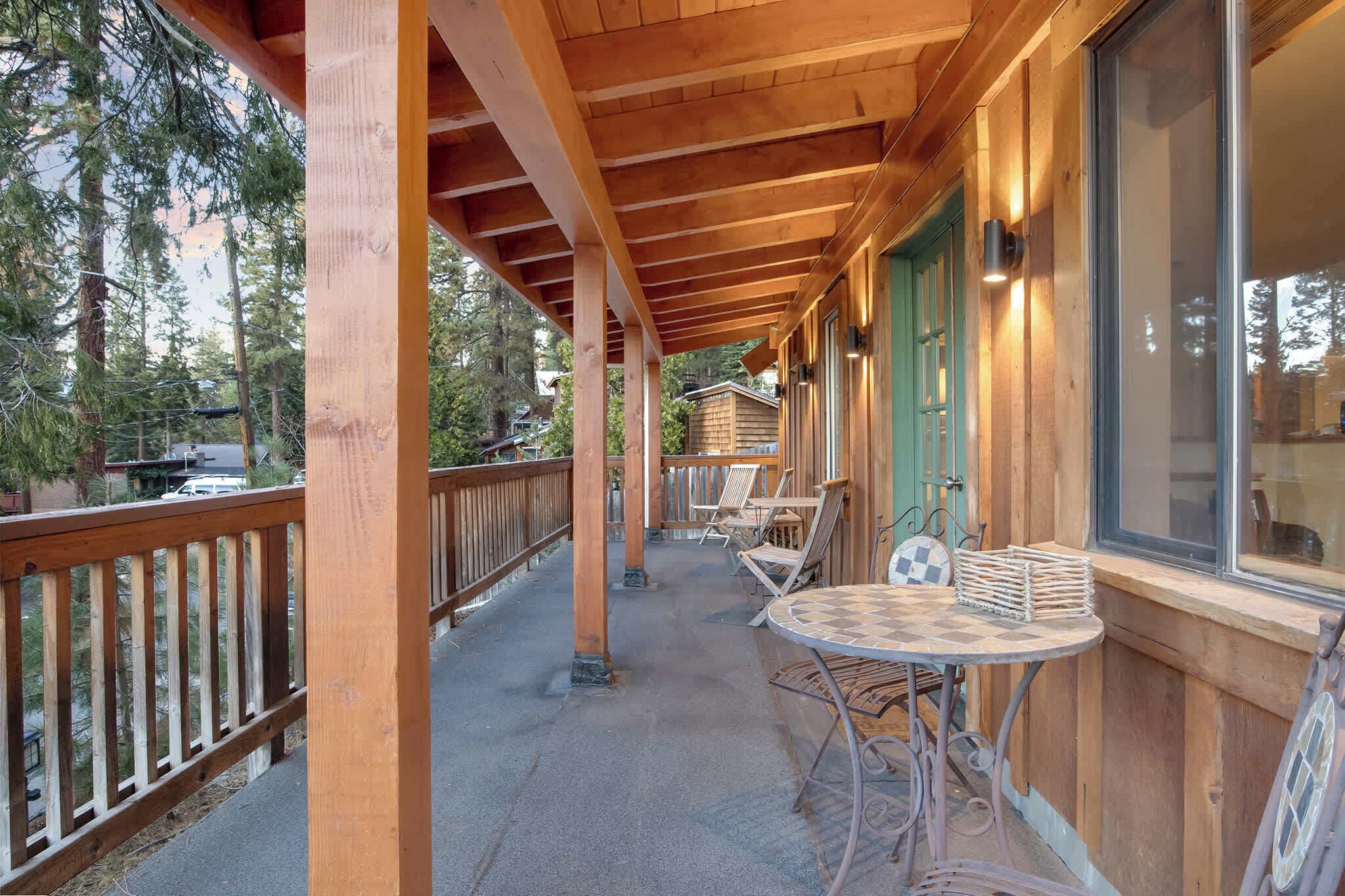 A wooden deck with a covered area, outdoor seating, and a view of a forested area.