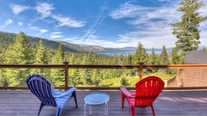 A wooden deck with two chairs and a small table, overlooking a forested landscape and a lake. - Chamberland Getaway Lake Views w/ Deck! (Homewood)