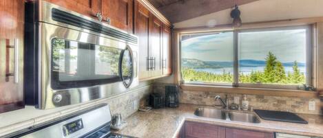 A kitchen with a stainless steel range, a microwave, and a window with a scenic view.